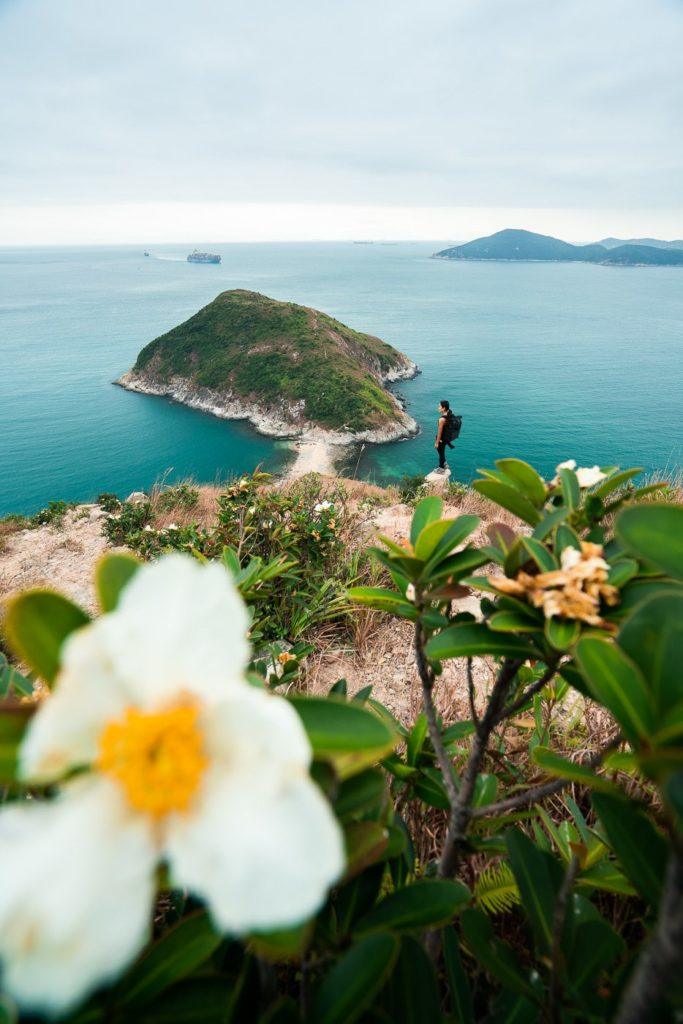 a person standing on top of a hill next to a body of water.