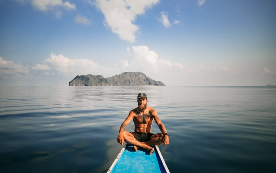 a man sitting on a boat in the middle of the ocean.