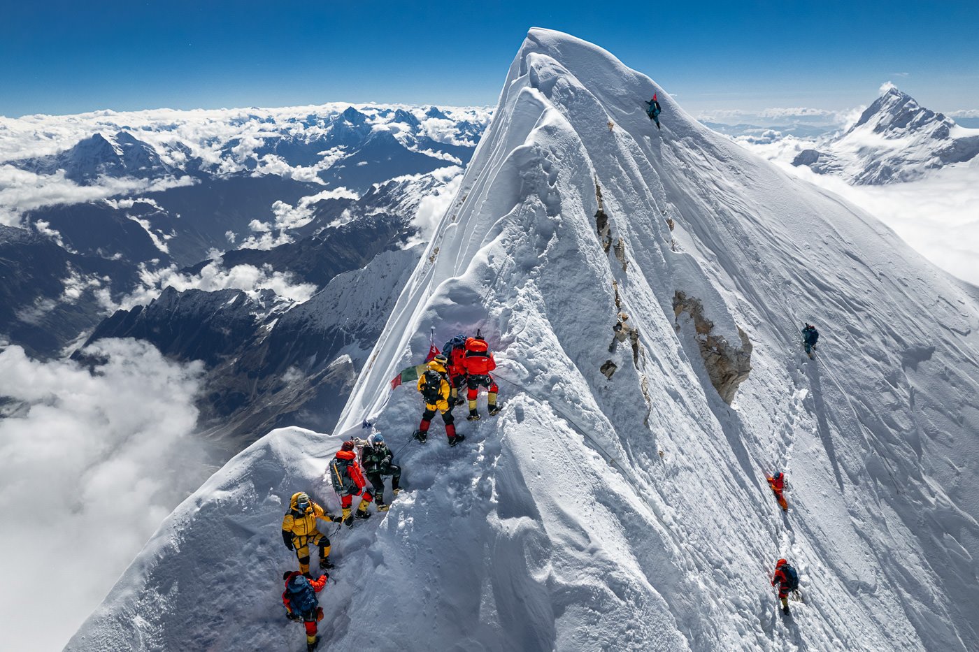 a group of people climbing up the side of a snow covered mountain