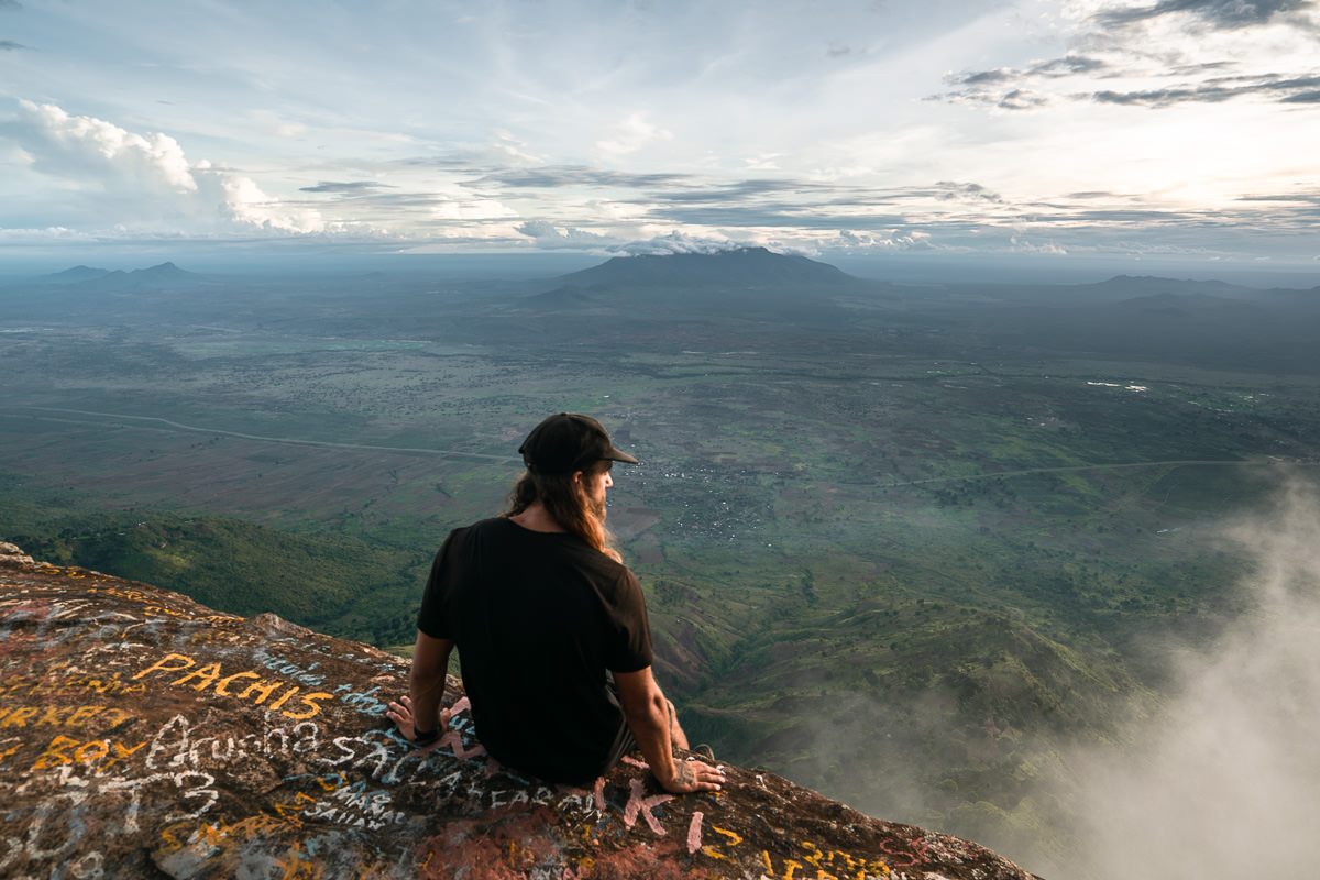 a person sitting on a rock looking out over a valley
