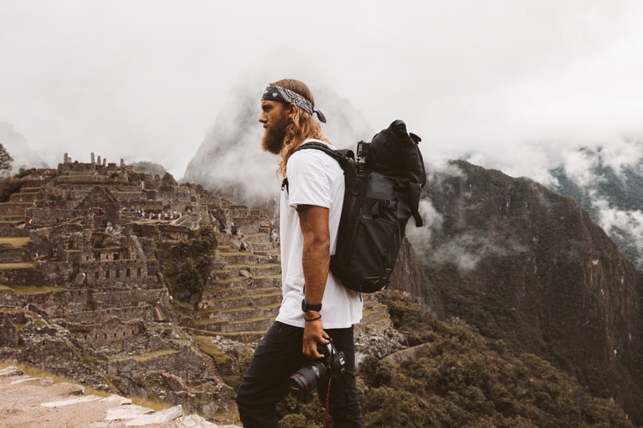a man standing on top of a mountain with a camera.