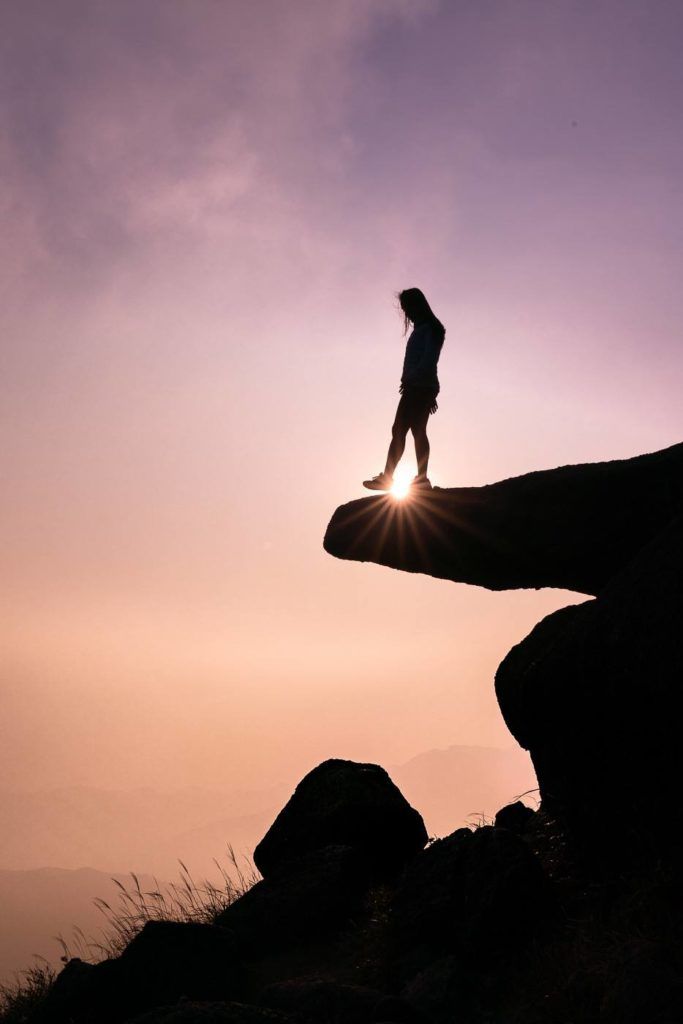 a person standing on top of a large rock.