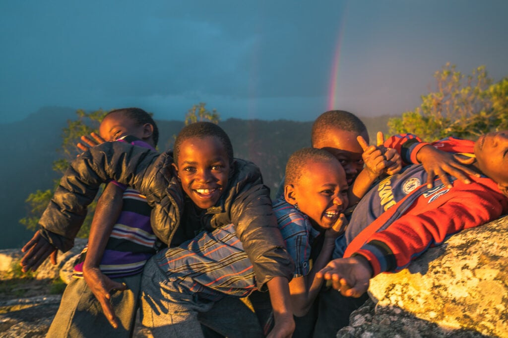 a group of children sitting on top of a rock